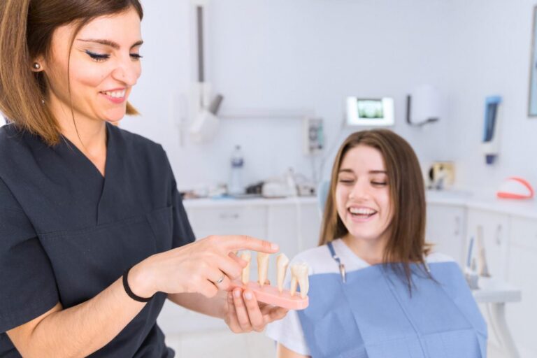 Dentist explaining dental implant options to a patient using a tooth model